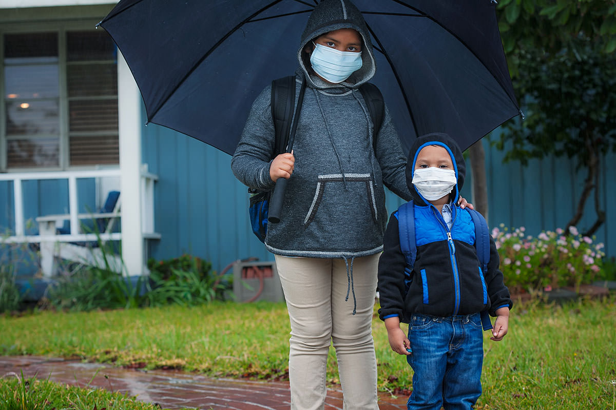brother and sister wait outside their home ready for school